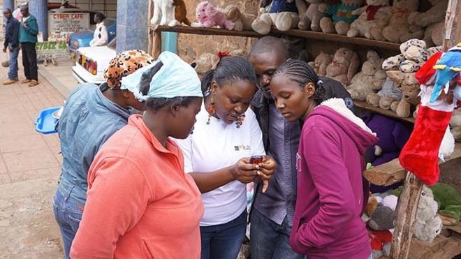 Группа кенийцев наблюдает за демонстрацией службы поиска работы M-Kazi