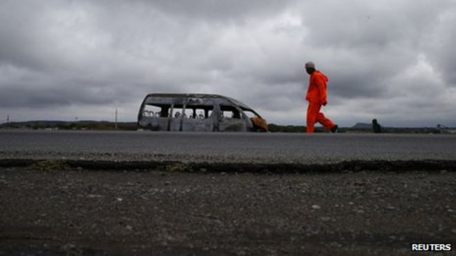 Шахтёр проезжает мимо останков микроавтобуса, сожженного в результате забастовки, рядом с шахтой, принадлежащей Anglo American Platinum, недалеко от Рустенбурга, в северо-западной провинции, 12 октября 2012 года
