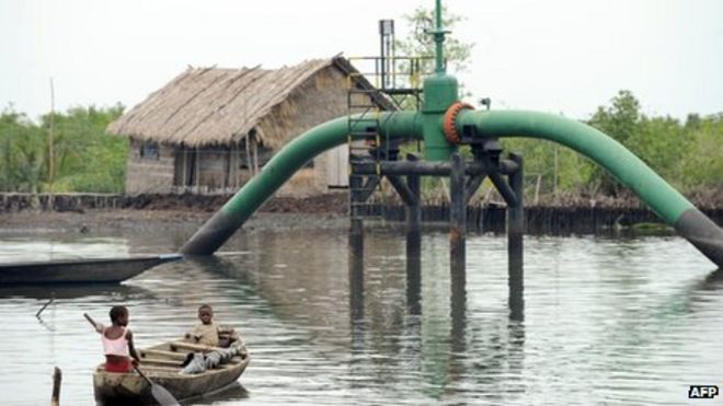 Children in a boat pass an oil pipeline head near their home in Rivers state April 2011