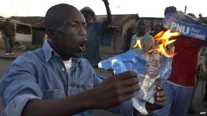 A man burns an election poster in the wake of election results in Kenya in December 2007 which has sparked violence in some areas