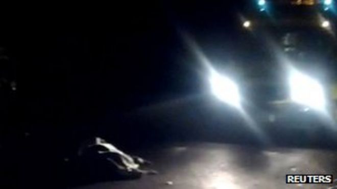 Неподвижное изображение с видео с любительской камеры показывает закрытое тело в Вейбридже, рядом с которым стоит полицейская машина, 10 ноября
