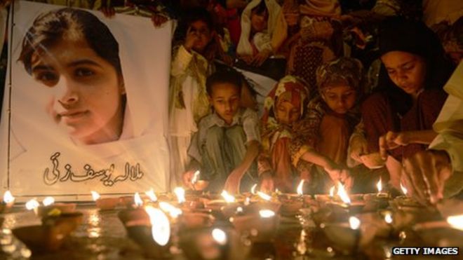 Дети зажигают свечи и держат фотографию Малалы Юсуфзай