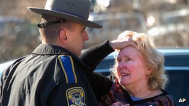 Расстроенная женщина разговаривает с полицейским возле школы Сэнди Хук