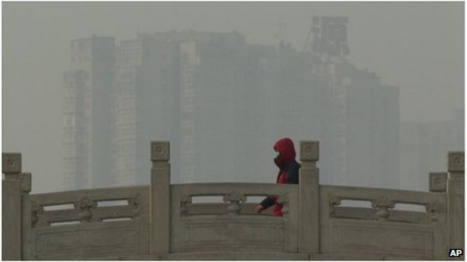 Человек в маске идет по мосту в темном Пекине (14 января 2013 г.)
