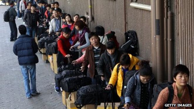 Посетители из материкового Китая ждут в очереди со своими товарами возле железнодорожной станции Шеунг Шуй в Гонконге