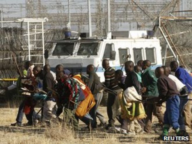 Протестующие шахтеры обращаются в полицию до того, как их обстреляли возле рудника Марикана 16 августа 2012 года