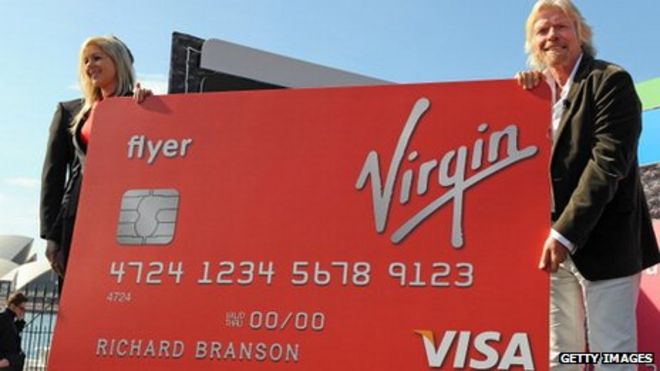 Ричард Брэнсон держит большую кредитную карту Virgin Money