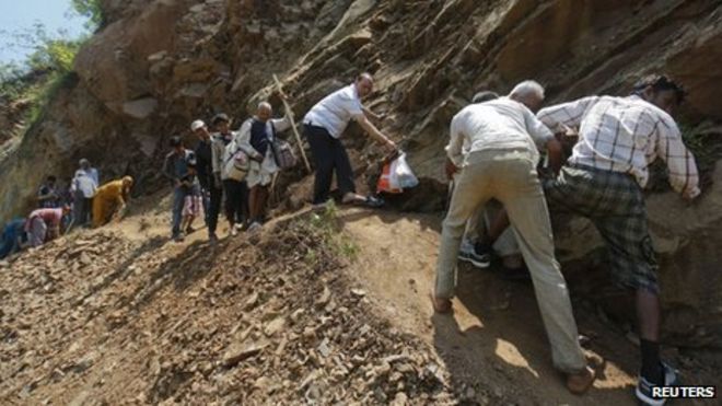 Паломники пытаются пересечь тропу, поврежденную оползнем Рудрапраяг в гималайском штате Уттаракханд 20 июня 2013 года.