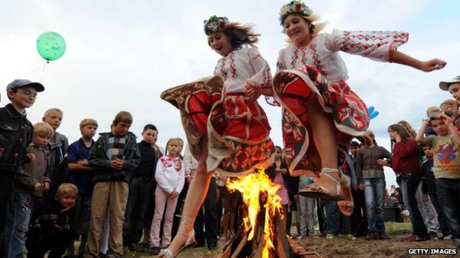 Девушки перепрыгивают через костер во время празднования Ивана Купалы, праздника Святого Иоанна Крестителя, традиционного славянского православного праздника, посвященного летнему солнцестоянию