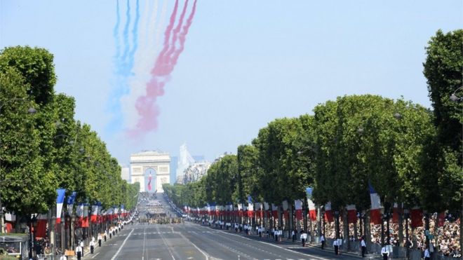 Девять самолетов ВВС Франции Patrouille de France выпускают следы красного, белого и синего дыма, цвета французского национального флага, когда они принимают участие в полете во время парада Дня взятия Бастилии на проспекте Елисейских полей, 2013