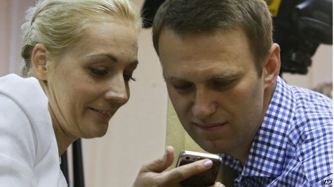 Российский лидер оппозиции Алексей Навальный и его жена Юлия смотрят на мобильный телефон во время судебного процесса в Кирове, Россия, 18 июля 2013 года.