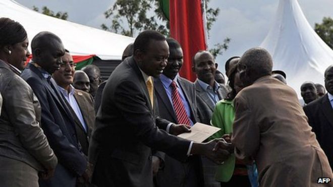 Президент Кении Ухуру Кеньятта и его заместитель Уильям Руто раздают чеки 7 сентября 2013 года в Элдорете в северной части Кении