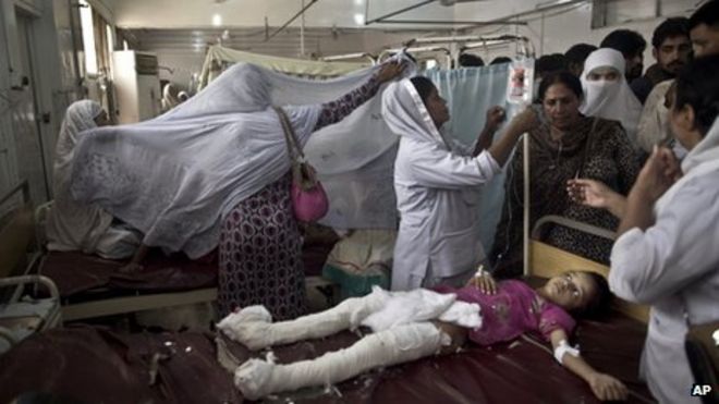 Пакистанская девушка, которая была ранена в результате нападения смертника на церковь, лежит на больничной койке в окружении родственников и медсестер