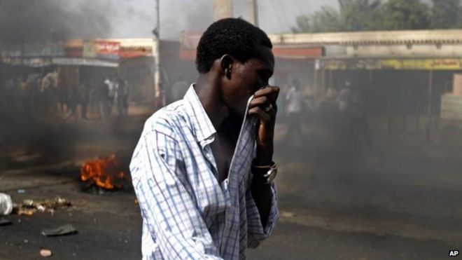 Суданский мужчина прикрывает рот от густого дыма после того, как протестующие сожгли шины, чтобы закрыть шоссе к северным городам на фоне волны волнений по поводу отмены субсидий на топливо правительством Судана в Кадро, в 15 милях (24,14 километра) к северу от центра Хартума, Среда, 25 сентября 2013 года.