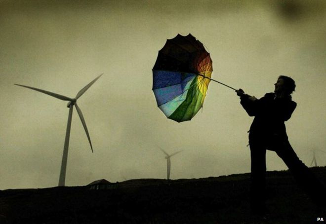 Человек с перевернутым зонтом от ветряной турбины в шторм