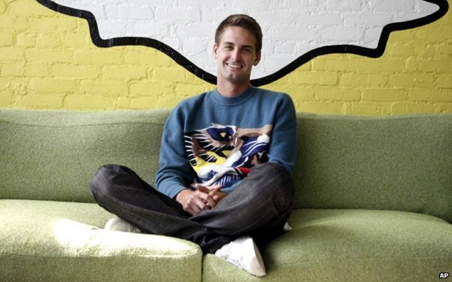 Эван Шпигель сидит под логотипом Snapchat