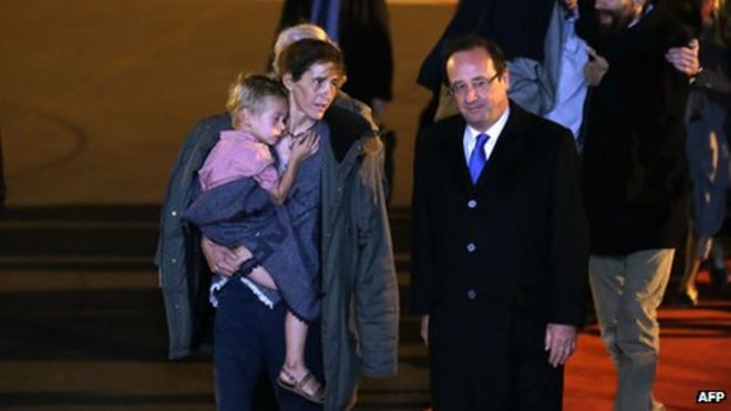 Президент Франции Франсуа Олланд (на переднем плане справа) беседует с Альбане Мулен-Фурнье, которая несет одного из своих детей, когда семь членов семьи Мулен-Фурнье прибывают из Яунде, в аэропорт Орли, недалеко от Парижа (20 апреля 2013 г.)