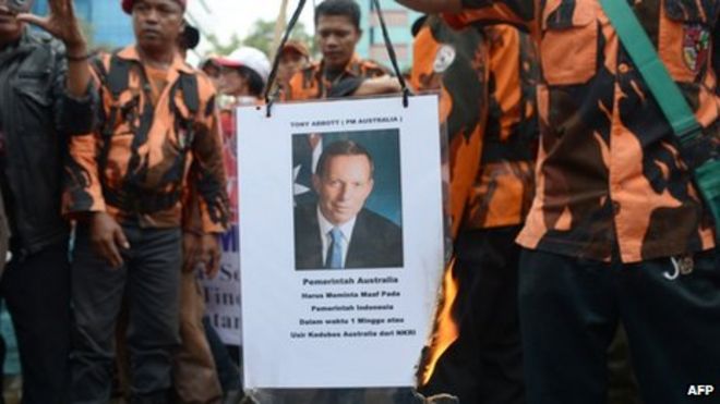 Члены Pemuda Pancasila обжигают фотографию премьер-министра Австралии Тони Эбботта во время протеста против утверждений о том, что австралийские шпионы напали на телефон президента Индонезии Сусило Бамбанга Юдхойоно возле посольства Австралии в Джакарте 26 ноября 2013 года.