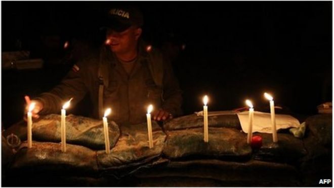 Колумбийский полицейский зажигает свечи для погибших коллег в Инзе, Каука