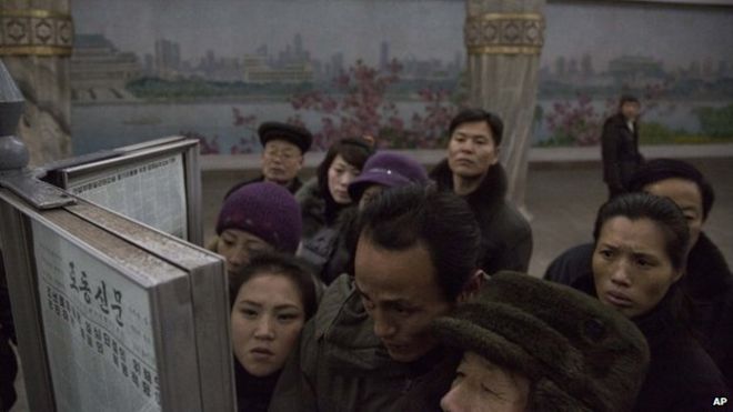 В пятницу, 13 декабря 2013 года, пассажиры северокорейского метро собрались вокруг общественной газетной стойки на платформе поезда в Пхеньяне, Северная Корея, чтобы прочитать заголовки о Чан Соне Тхаке