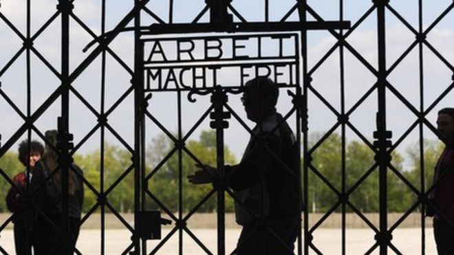 Посетители проходят мимо ворот с надписью «Работа делает тебя свободным» на мемориальной площадке бывшего нацистского концентрационного лагеря в Дахау, изображение файла