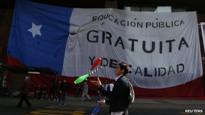 Студент-протестующий жонглирует, проходя мимо чилийского флага во время демонстрации в Сантьяго 5 сентября 2013 г.