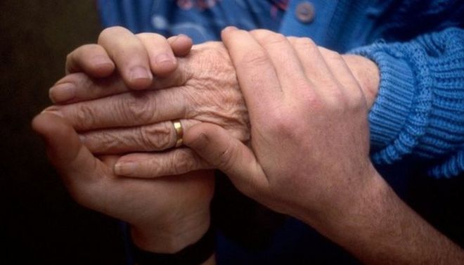 Молодой человек держит руки пожилого человека