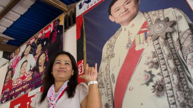 Хамсаен Чайтхеп, жена вождя деревни в Нхонг Хуу Линг, стоит у плаката Таксин Шинаватры