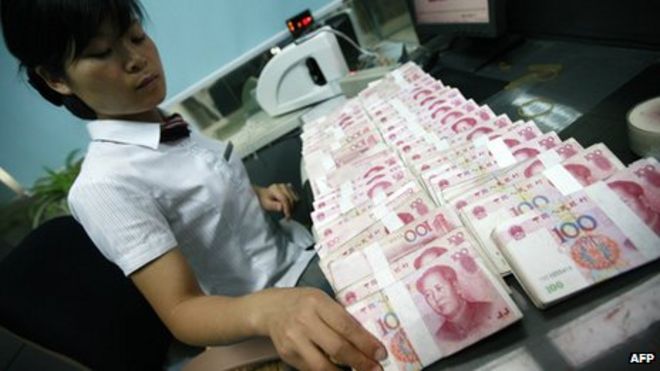 Сотрудник банка, считающий банкноты в юанях