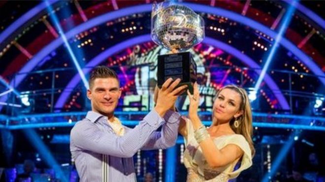Альяз Скорянец и Эбби Клэнси держат трофей «Строго прибывшие танцы» в блестящем мяче