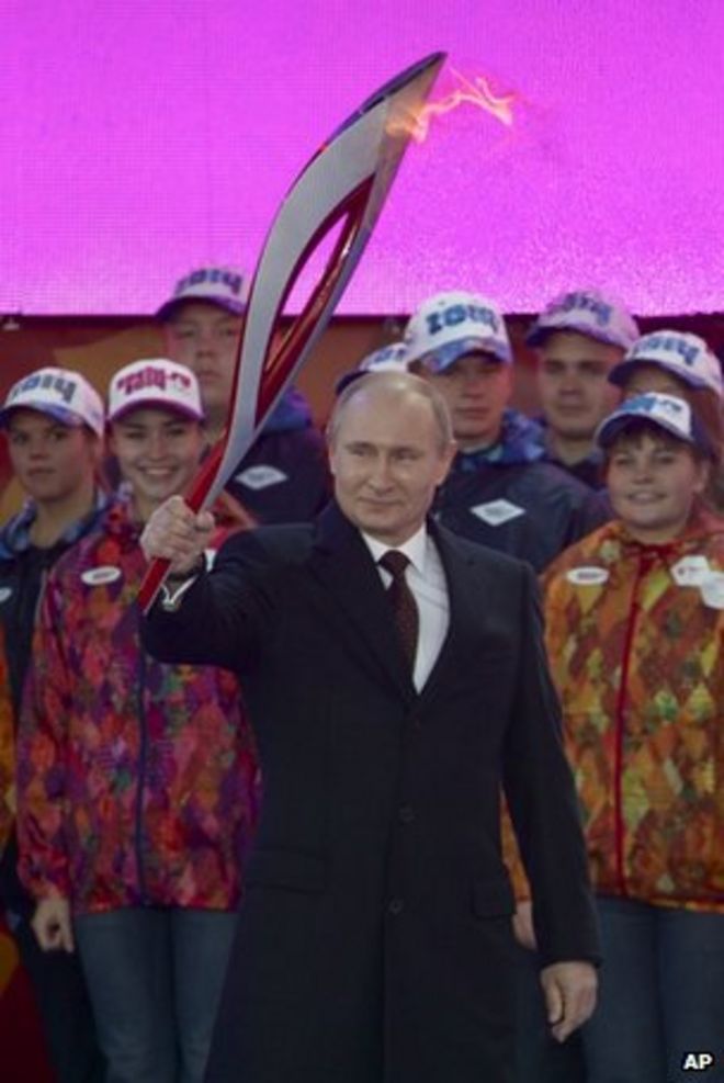 Президент России Владимир Путин размахивает олимпийским факелом на Красной площади 6 октября