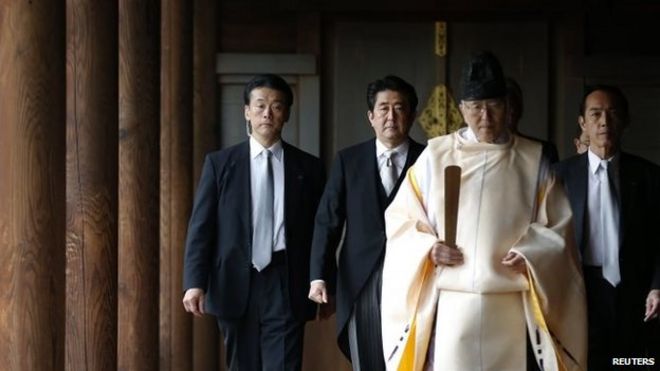 Синдзо Абэ (2-й л) во главе с синтоистским священником во время посещения храма Ясукуни в Токио 26 декабря