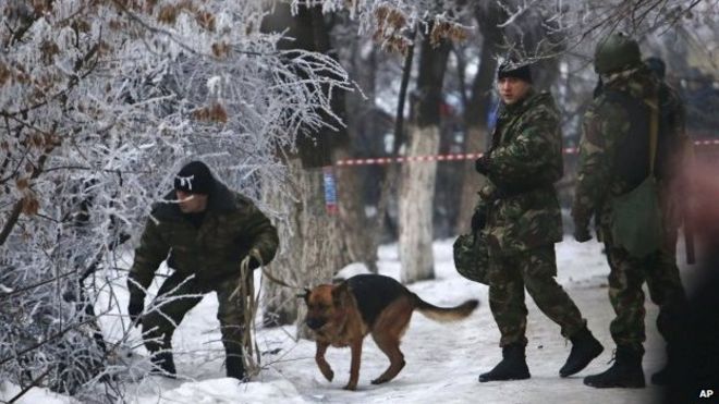 Сотрудники милиции со служебной собакой осматривают территорию вокруг места взрыва троллейбуса в Волгограде, Россия, понедельник, 30 декабря 2013 г.