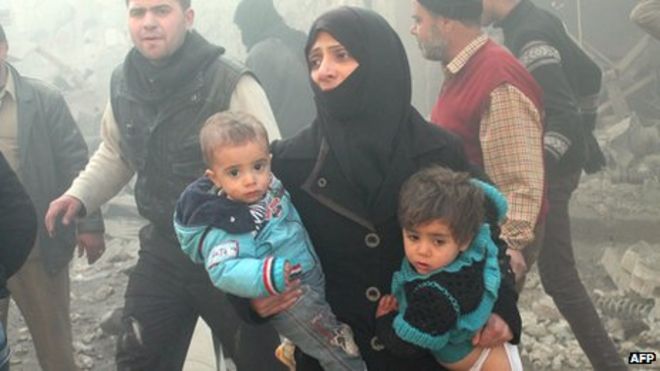 Сирийская женщина несет детей после авиаударов в Алеппо