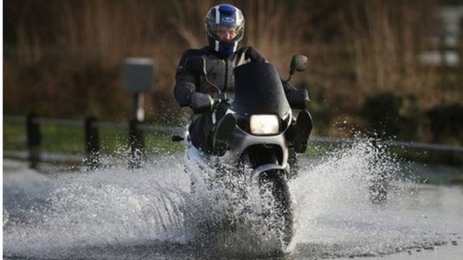 Мотоциклист едет по затопленной дороге в Суррее