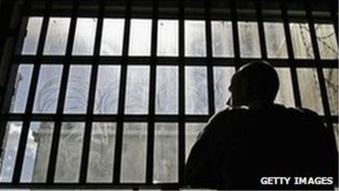 Заключенный смотрит в окно камеры