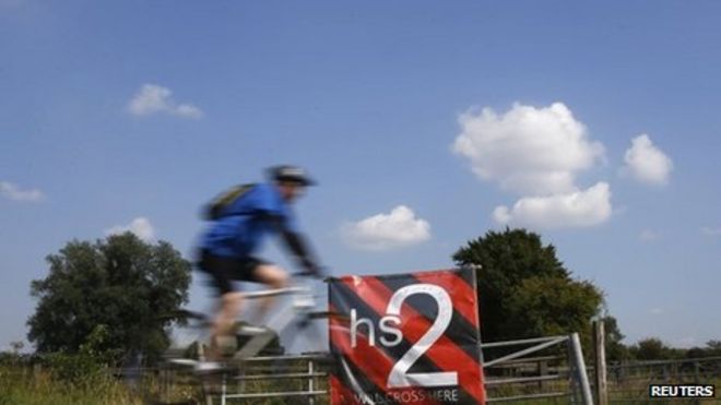 Человек проезжает мимо баннера с проектом высокоскоростной железной дороги (HS2) в Австрии, центральная Англия