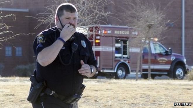Офицер полиции Розуэлла отвечает, когда сотрудники правоохранительных органов устанавливают периметр после ранней утренней стрельбы в средней школе Беррендо в Розуэлле, штат Нью-Мексико, 14 января 2014 г.