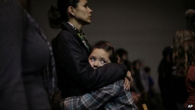 Девятилетняя Рэйлинн Холлоуэй обнимает свою мать Рианнон Холлоуэй (слева) во время молитвенного бдения в отношении жертв стрельбы в средней школе Беррендо в Розуэлле, Нью-Мексико 14 января 2014 года