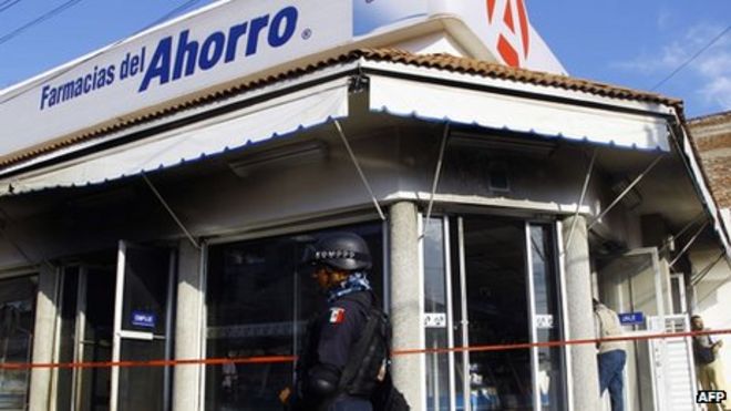 Сотрудники мексиканской федеральной полиции стоят на страже у аптеки, на которую напали организованные преступные группировки в Апацингане 15 января 2014 года