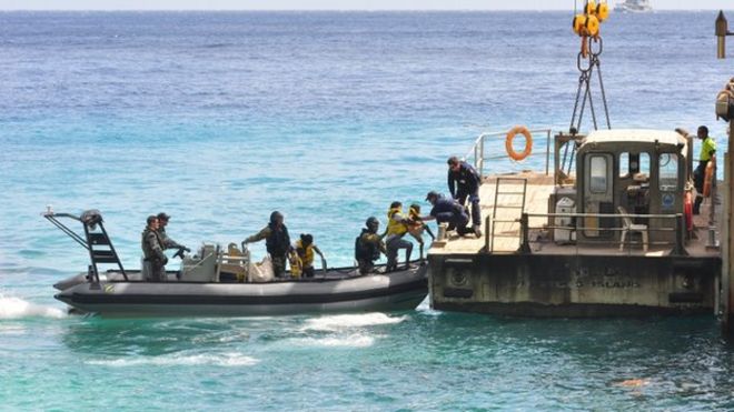Предполагаемые лица, ищущие убежища, прибывают на остров Рождества после того, как 3 августа 2013 года они были перехвачены ВМС Австралии