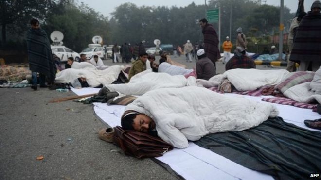 Сторонник главного министра Нью-Дели Арвинд Кейривал опускает голову на портфель на рассвете после того, как около 200 протестующих провели ночь на улице с Кейривалом во время сидячей акции протеста в Нью-Дели 21 января 2014 года.