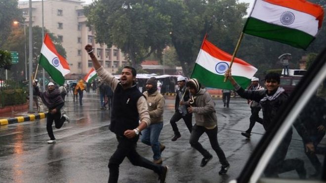 Сторонники главного министра Нью-Дели Арвинда Кейривала несут индийские флаги, когда они бегут рядом с районом, где Кейривал провел ночь во время сидячей забастовки в Нью-Дели 21 января 2014 года
