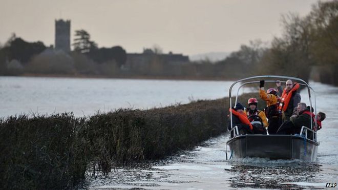 Жителей перевозят на лодке по паводковой воде в отсечной деревне Мучелни в Сомерсете, юго-западная Англия, 27 января 2014 года