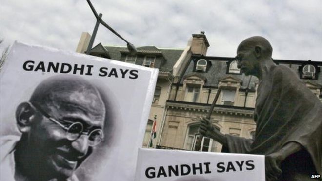 Активисты движения за мир держат плакаты с фотографиями покойного индийского лидера Мохандаса Карамчанда Ганди под его статуей перед посольством Индии в Вашингтоне.