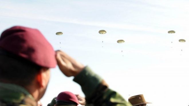 Член парашютного полка приветствует сброс парашюта на 3 пара в Мемориале Пегаса в Ранвилле, Нормандия, в ознаменование 65-й годовщины высадки в день Д.
