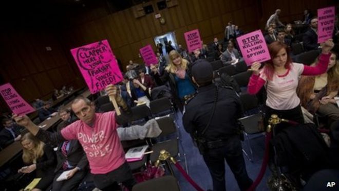 Офицер полиции Капитолия следит за действиями сотрудников Code Pink, пока они держат вывески на Капитолийском холме в Вашингтоне 29 января 2014 года