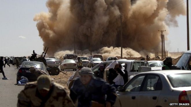 Бойцы оппозиции бегут в укрытие, когда ВВС Ливии атакуют нефтяной город Рас-Лануф, к западу от Бенгази