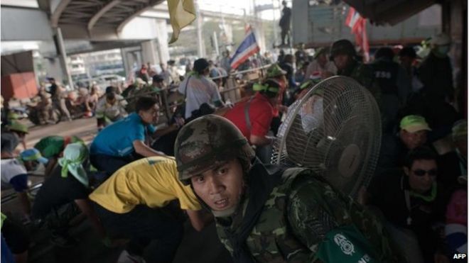 Солдат тайской армии (спереди) и антиправительственные демонстранты укрываются, поскольку взрывы и выстрелы из пистолета открываются во время столкновений с тайскими протестующими на выборах (не видно) в Бангкоке 1 февраля