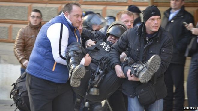 Люди помогают раненому полицейскому, когда в Сараево столкновения антиправительственных демонстрантов с полицией 7 февраля 2014 г.